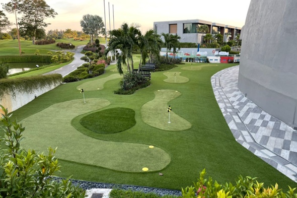 Synthetic grass golf course with multiple holes, flags, and a scenic view.